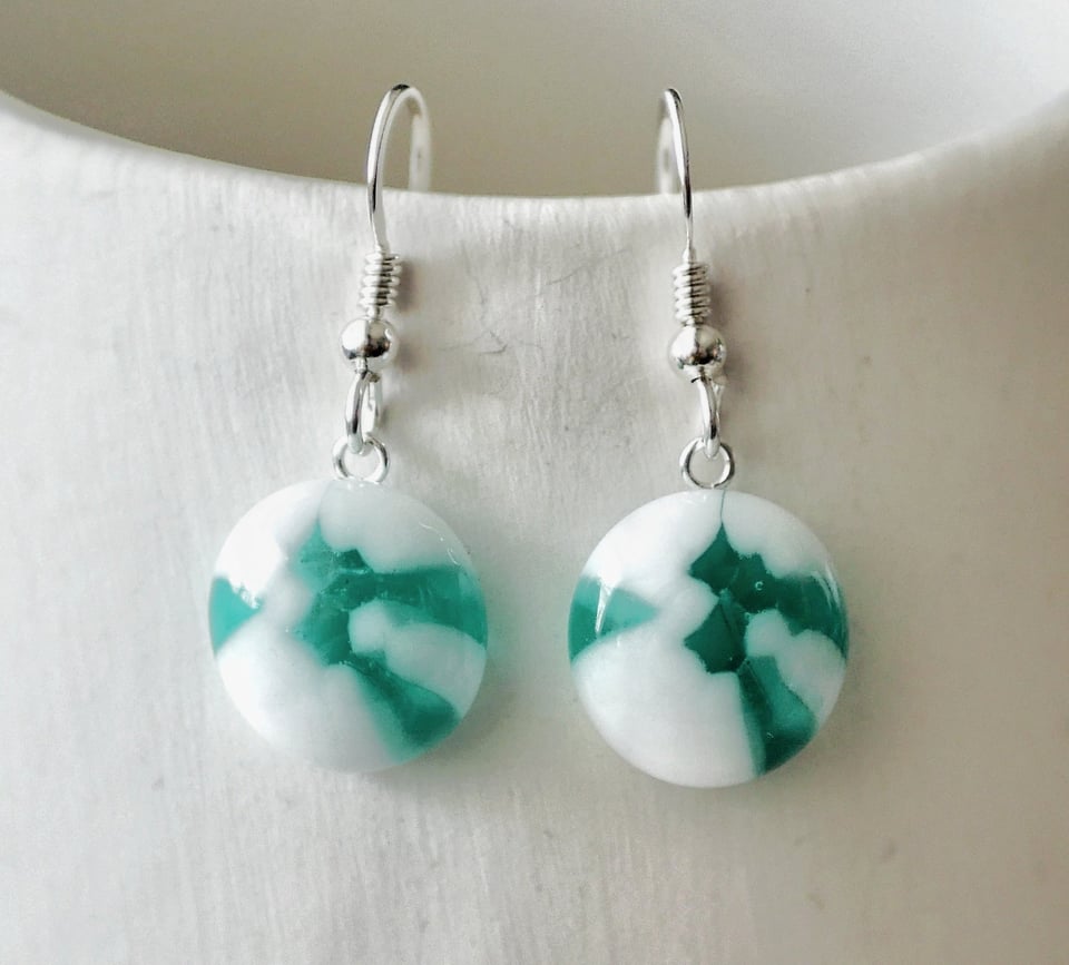 earrings with a clear teal and opaque white design that is the same on both earrings
