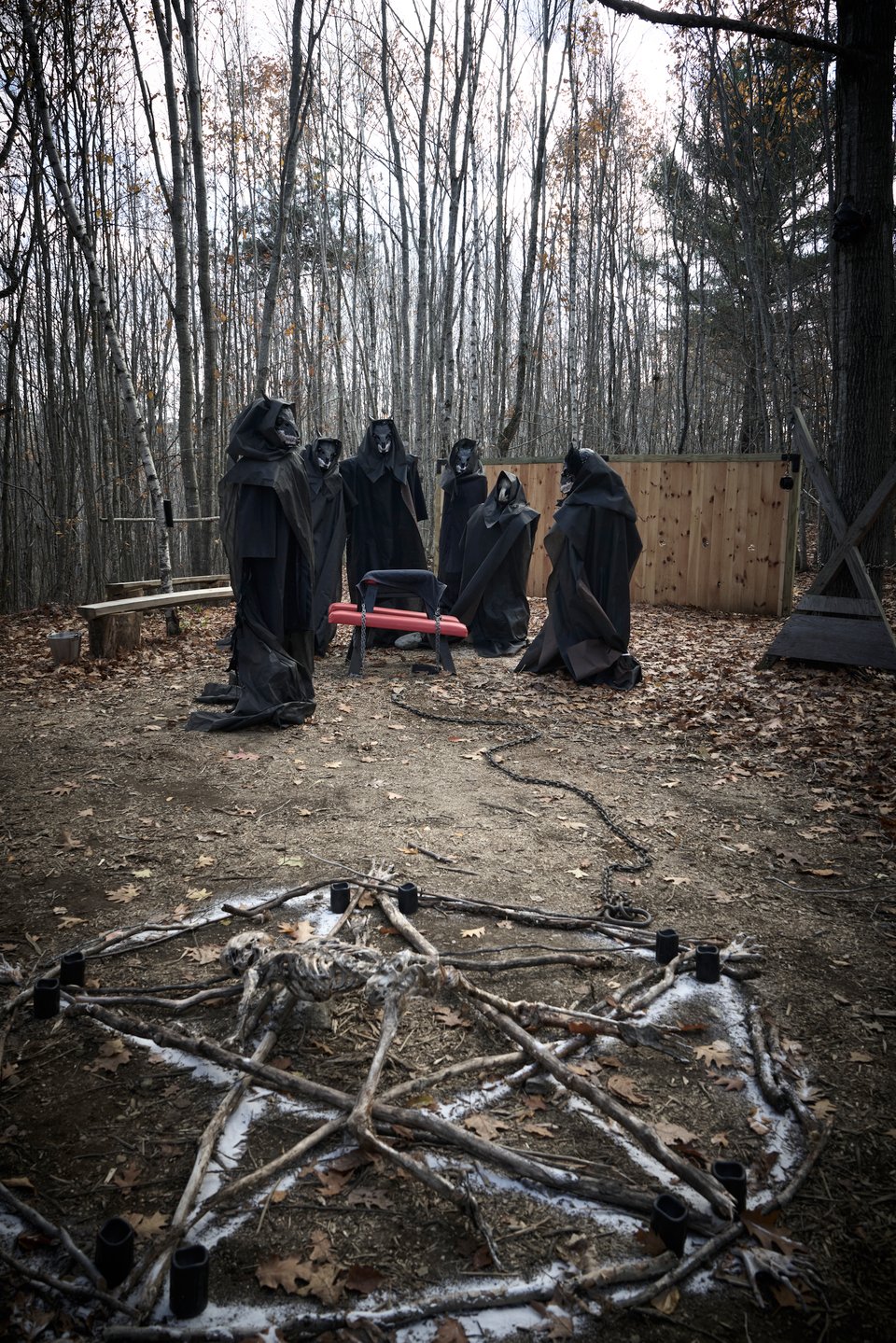 skeletal pentagram in foreground, coven of black robed figures in backround