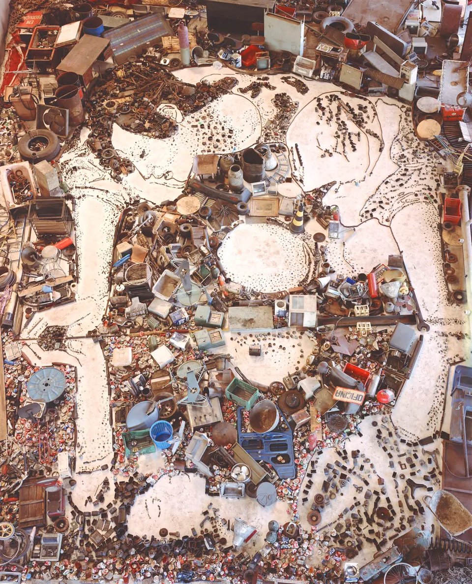 photo of a Narcissus-figure, contemplating itself, in a field of junk.