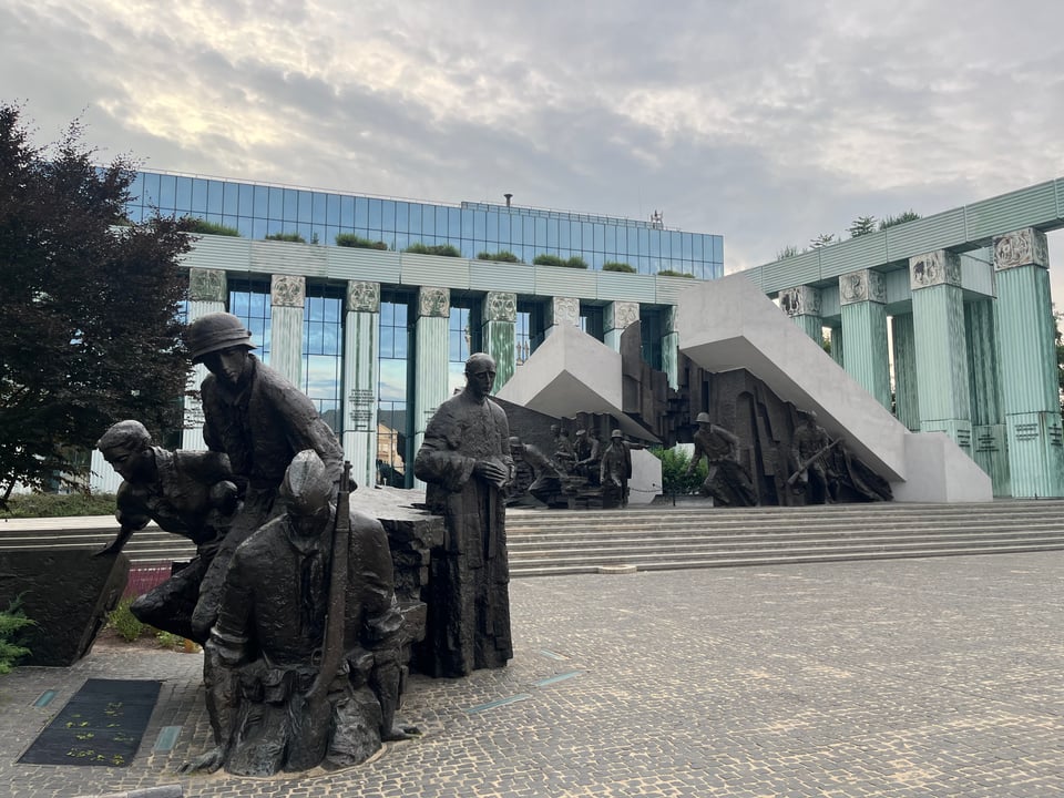 Black statues of soldiers, priests, messengers leaping outwards as if in motion
