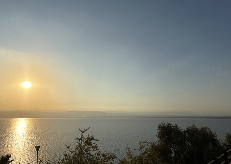A sunset over a body of water, with land in the distance