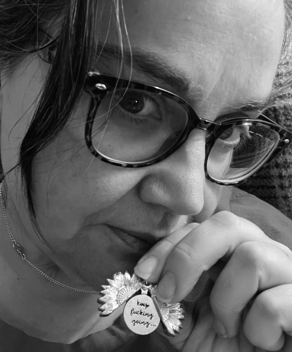 It's a picture of me, holding a pendant in my hand. The pendant opens up to show a plate that reads, "Keep fucking going."