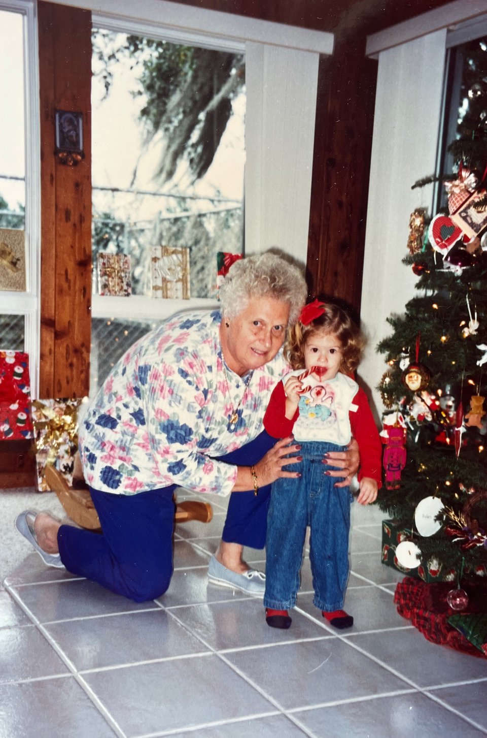 Image of Nana kneeling next to me, probably at age three. I have a candy cane in my mouth, and we're standing next to a Christmas tree, with presents on a windowsill behind us.