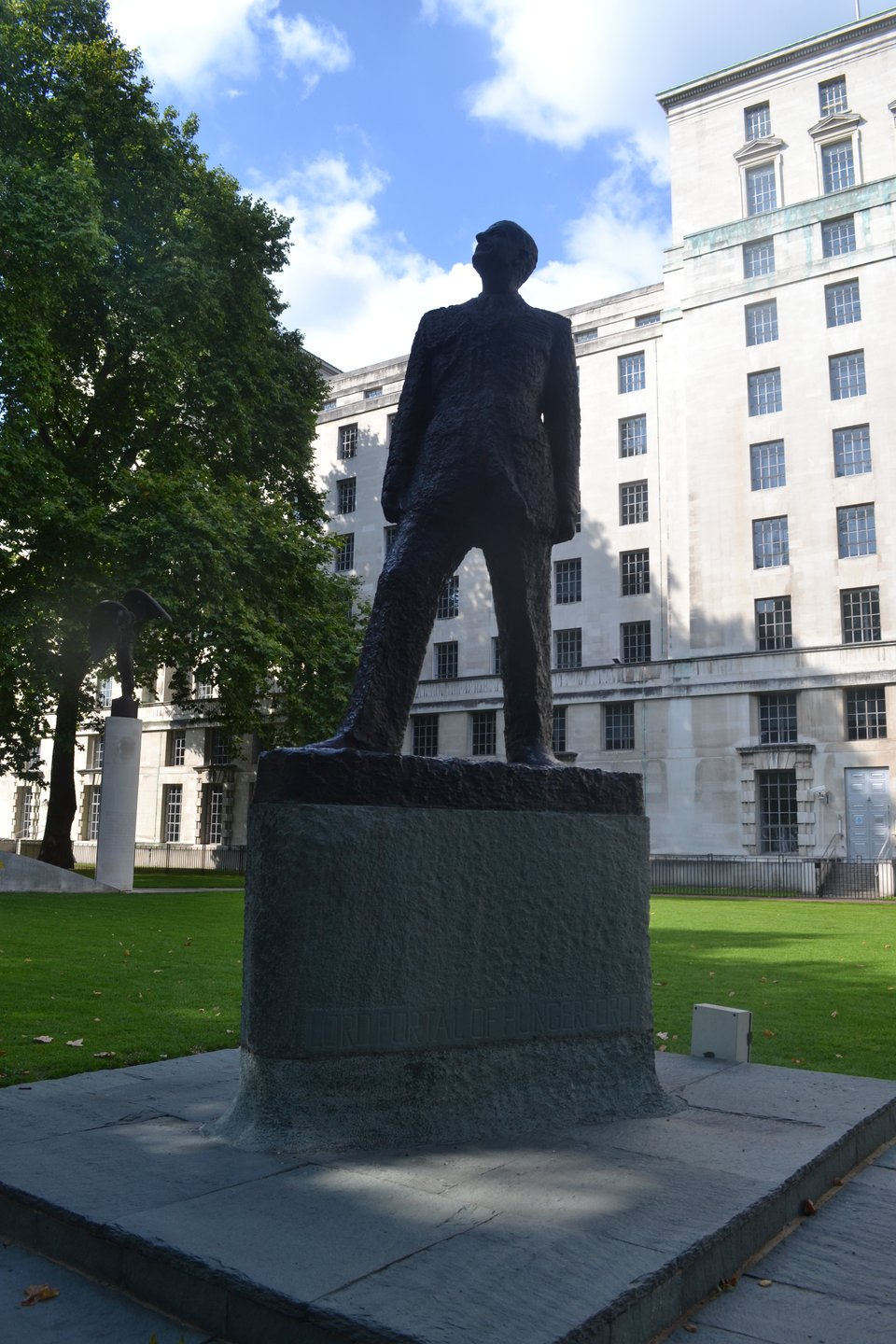 A statue of a man in a suit on a high plinth. He's looking skywards...or possibly down his nose at you. A tall 18th century building is behind.