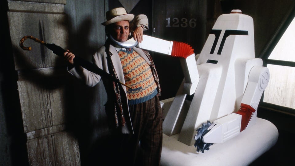The Seventh Doctor struggles in the grip of a Cleaner.