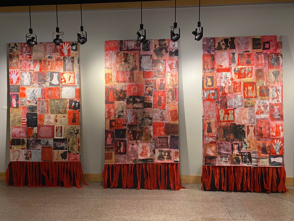 three large scale substrates with red hands and dress prints collaged on surface with a skirt on bottom of form