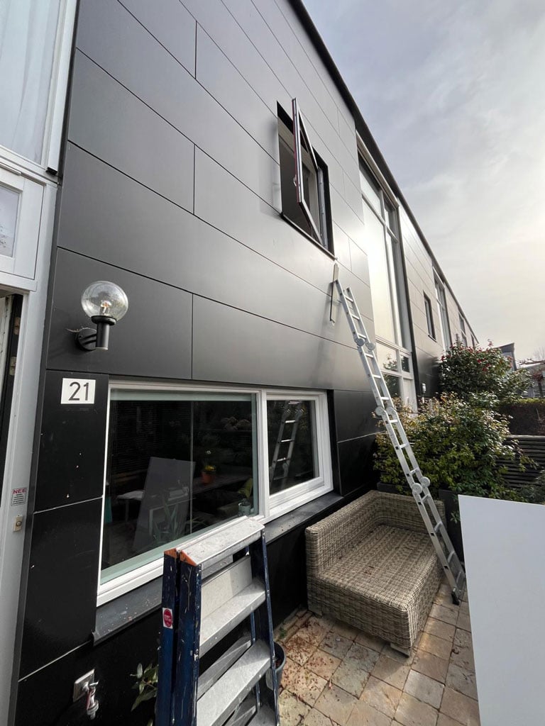 The outside of a house is shown. A ladder leans against the house almost reaching the window that is being replaced.
