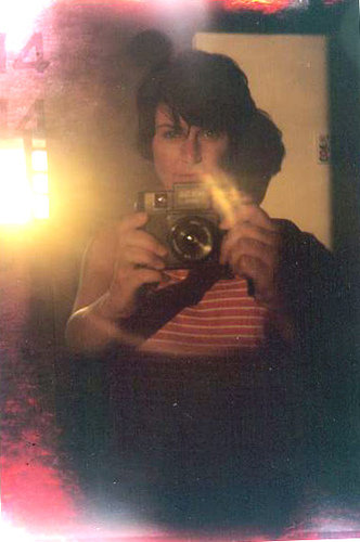 a self portrait of a woman in a mirror. the image has light leaks and double-exposure because I used a Holga