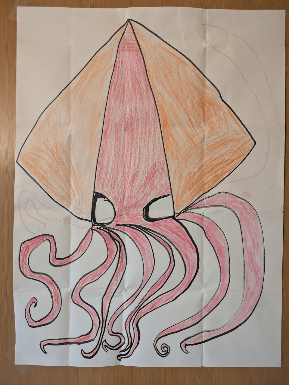 Photo of a poster taped to a wooden door. The paper is filled by an enormous red squid with orange fins and very large eyes. The squid's eight arms are wonderfully dynamic and its two elastic tentacles are appropriately long and thin.