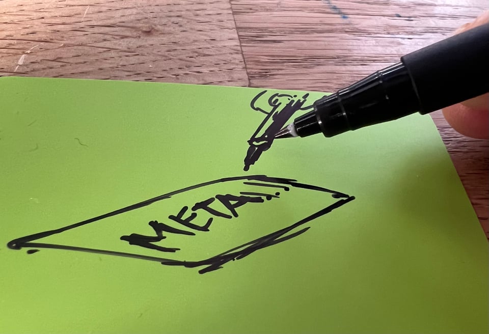 a person writing the word meta on an Artefact Card