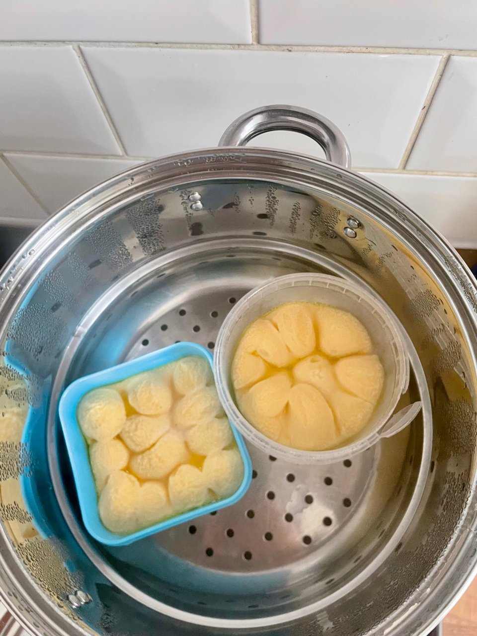 Two containers in a steamer with egg bubbling inside them