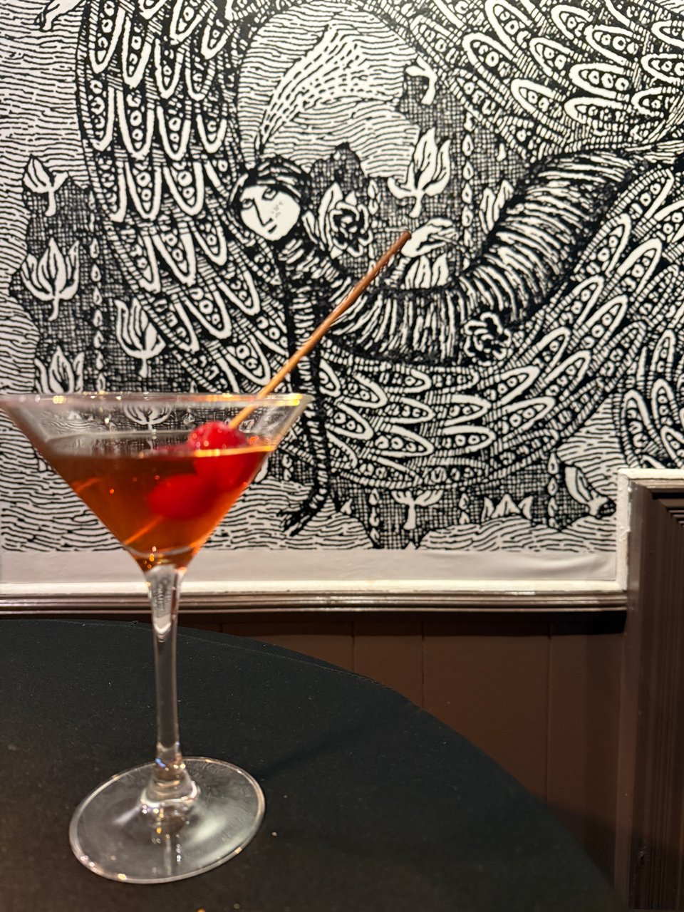 cocktail in cone glass with cherries on table in front of Edward Gorey drawing at the Society of Illustrators, New York CIty
