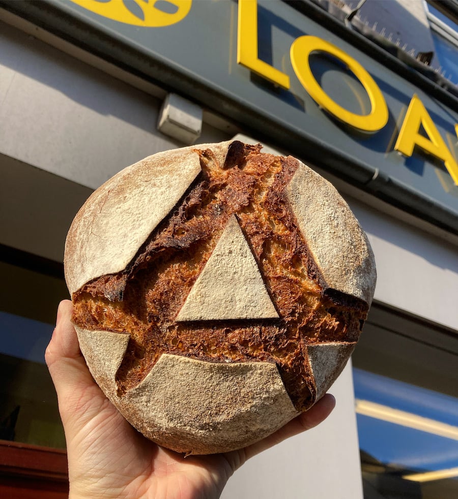 Loaf of bread held aloft in front of the Loaf shop logo