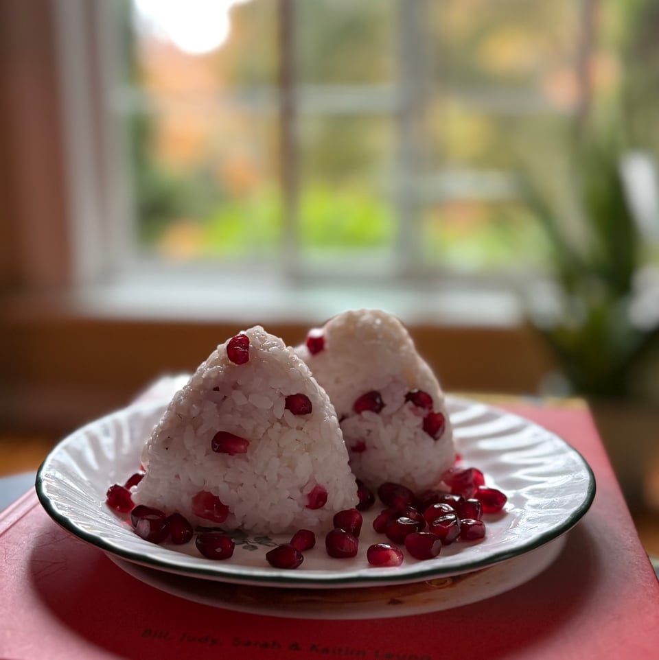 Onigiri rice pebbled with pomegranate seeds.
