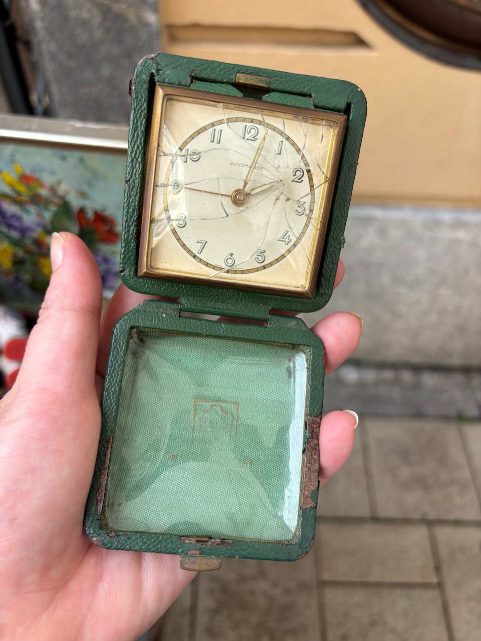 A clock in a folding case, the glass smashed and the hands stopped at two minutes past two