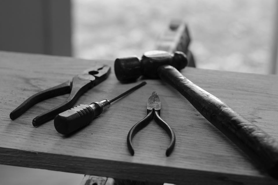 A black-and-white photo of some tools on a piece of wood.  Photo by Hunter Haley on Unsplash.