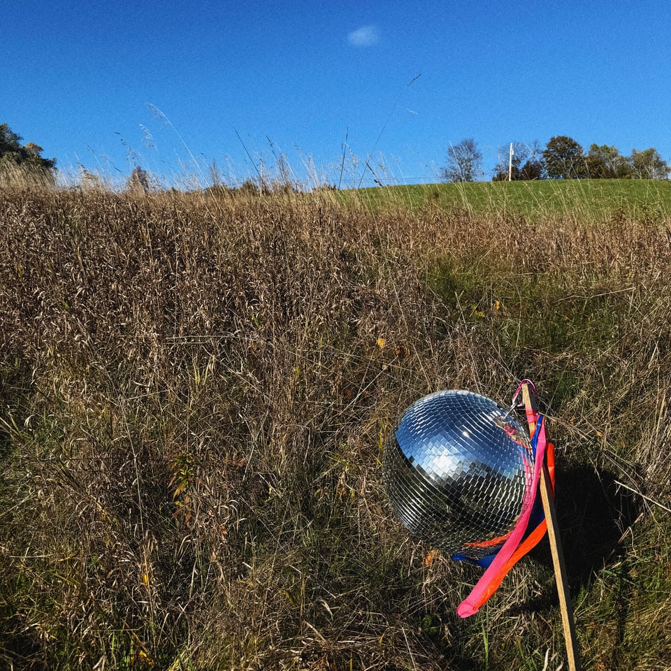 a disco ball in a hay field under a clear autumn sky
