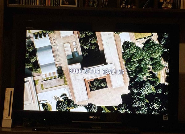 My television, and on it an aerial view of a building, and over that, in white letters, the words Burn After Reading