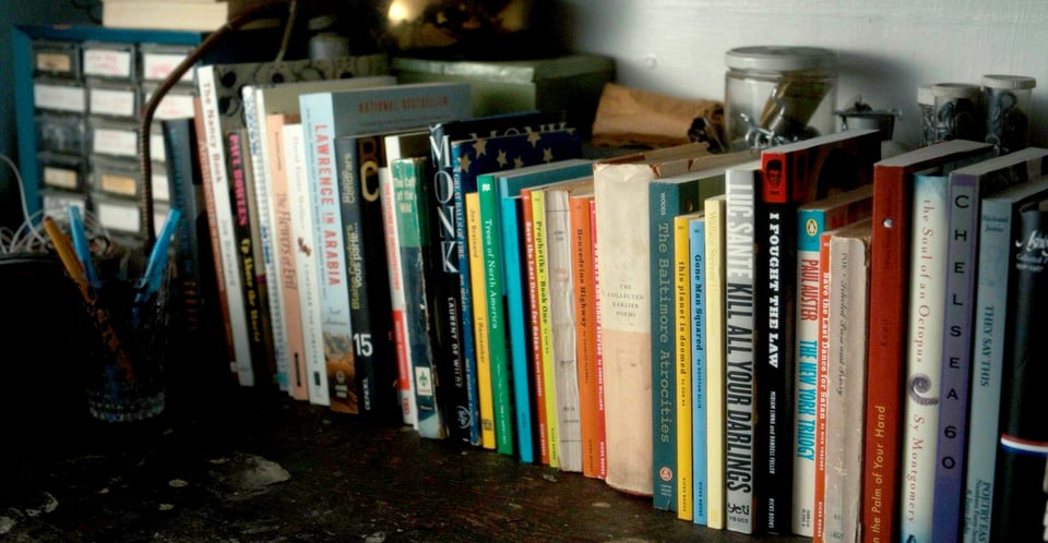 A small shelf of books in a basement workshop.