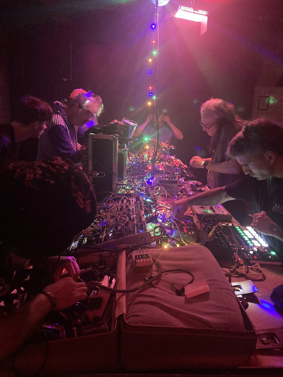 A group of performers and synths in a lit club
