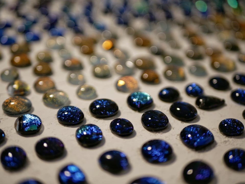 kiln shelf with dichroic cabochons, only a little bit in focus, very sparkly