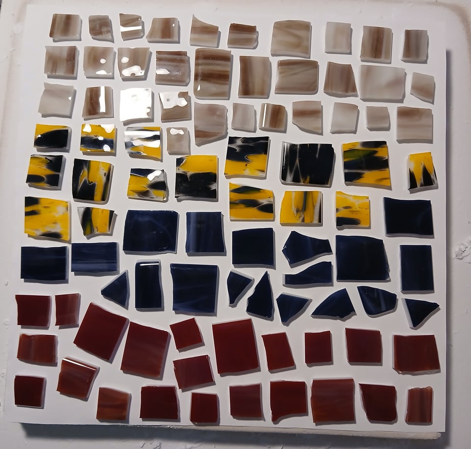 kiln shelf with brown yellow/black, dark blue and red pieces of glass