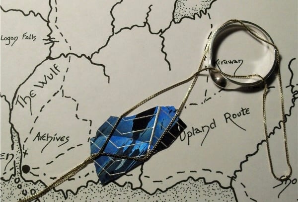 An illustrated map with a blue jewel and a silver ring on top