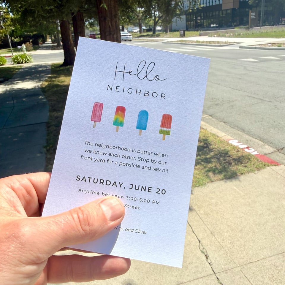Photo of a party invitation with popsicles on it, reading, "Hello Neighbor. The neighborhood is better when we know each other. Stop by our front yard for a popsicle and say hi!"