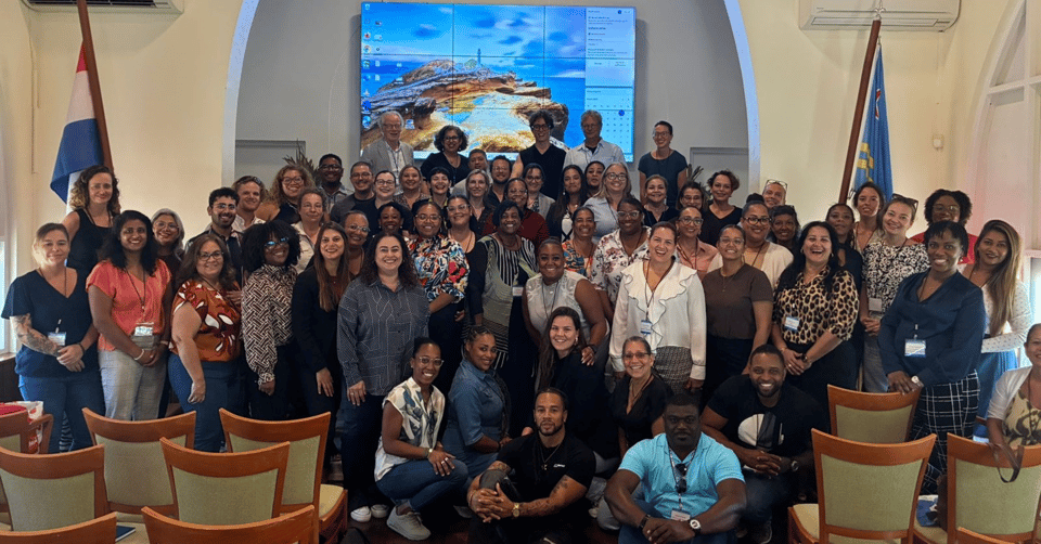 A seminar participant group picture, with the Aula of the University of Aruba filled up and people having to sit in order to have everyone on the group picture.