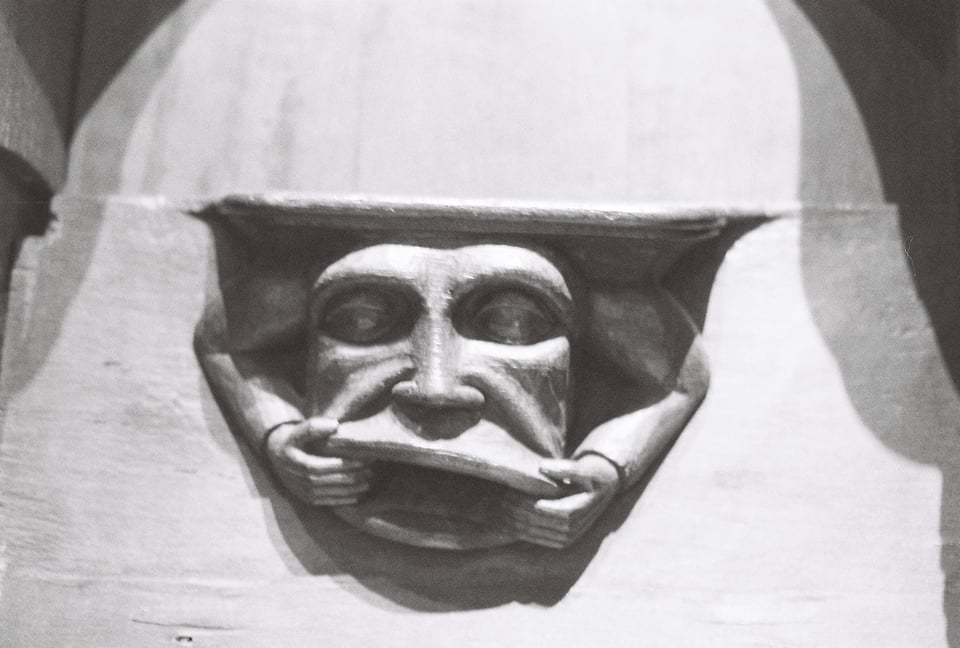 A gargoyle on a prayer bench, from the Met Cloisters. Pictured in closeup, black and white.