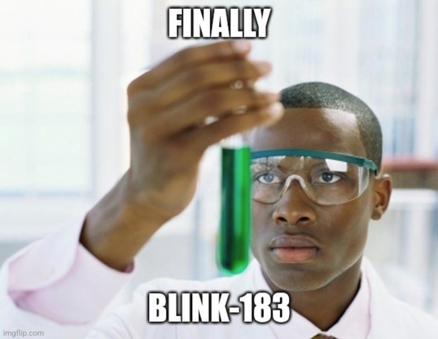 Photo of a black male scientist wearing a labcoat and safety glasses, holding up a vial filled with green liquid. The overlaid text reads: Finally, Blink-183