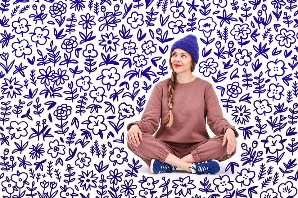 Photo of young woman sitting down on a white background surrounded by lots of hand-drawn flowers