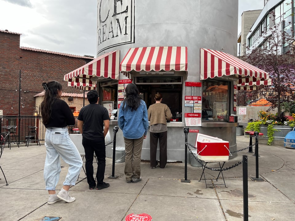 A group of people visiting an ice cream shop.