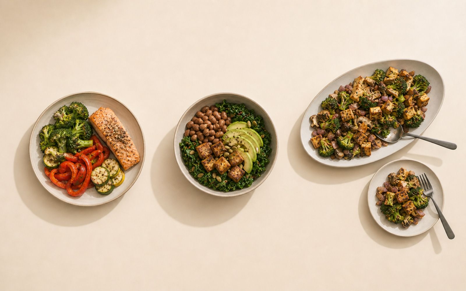 Three lower-carbohydrate meals photographed from above: a plate of salmon with broccoli, peppers, and squash; a bowl of kale, chickpeas, tofu, and avocado; and a shared platter of tofu, broccoli, and mushrooms with one portion served onto a side plate.