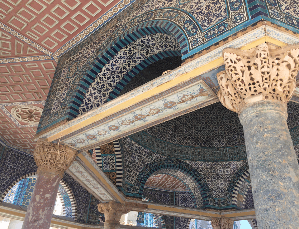 A view from under the Dome of the Rock showing elaborate tile work, arches, and columns
