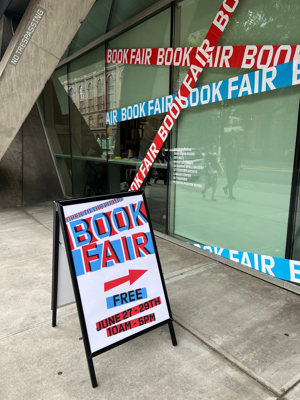 "Book fair" sandwich board sign on sidewalk in front of windows with big "Book fair" signage, all set in the typeface Export