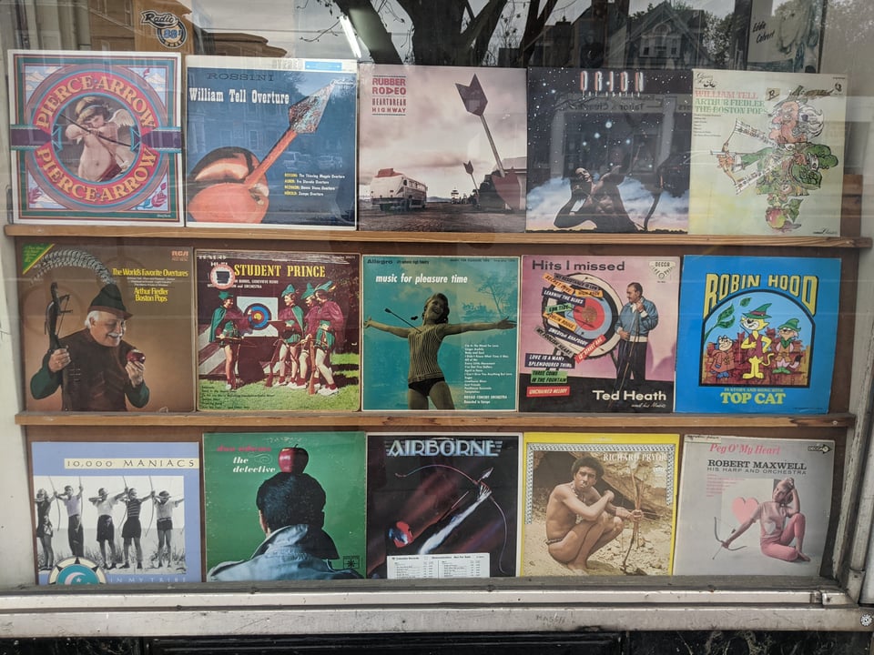 Fifteen record covers involving bows and arrows, including albums by Richard Pryor, 10,000 Maniacs, Arthur Fiedler and the Boston Pops and the William Tell Orchestra.