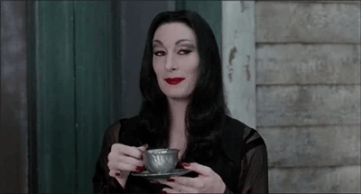 A gif of Morticia Addams drinking a teacup and raising a finely manicured eyebrow