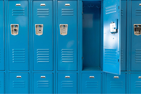 Photo of a row of blue metal lockers, like the ones in high schools, with one door open and all the others closed.