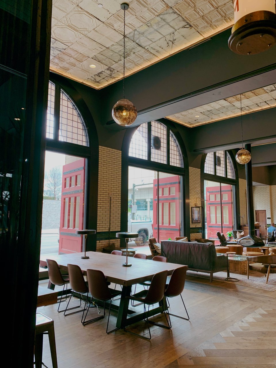 A hotel lobby with high ceilings, arched windows, and red doors