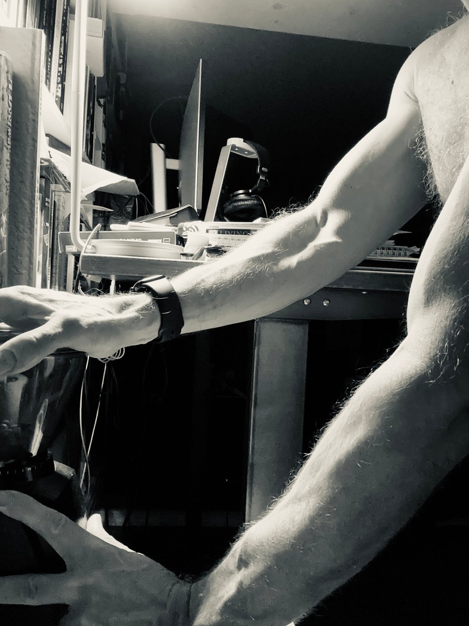 b/w photo of a man using an automatic coffee grinder. We can only see his pretty toned arms and hands and a little of his chest