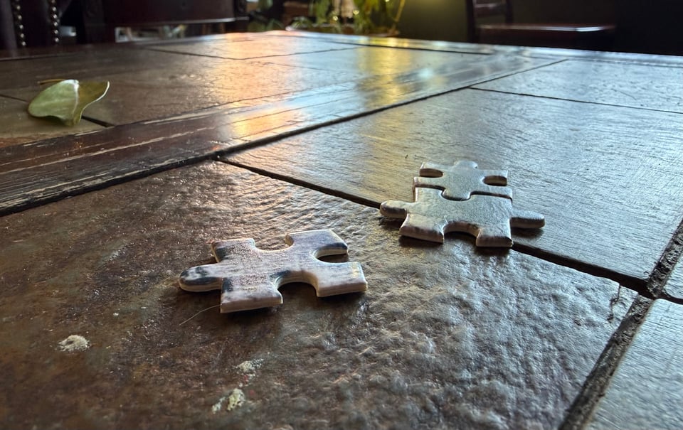 photo of 3 jigsaw-puzzle pieces on a brown tile table in a coffeeshop