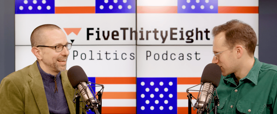 Dan begins to reply, smiling, while Galen looks at him conspiratorially