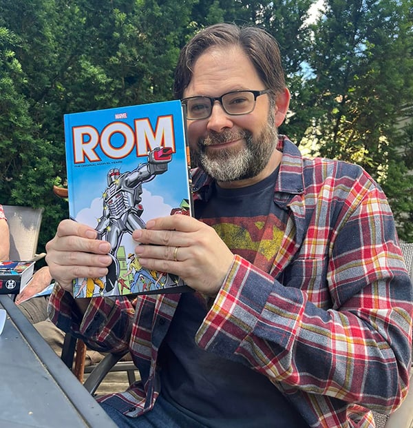 Me, sitting outside, holding up a copy of the Rom Omnibus that I got for my birthday.