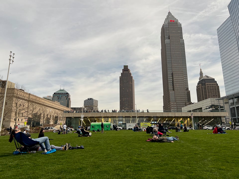 People sitting on the grass on the Mall in front of buildings in Cleveland.