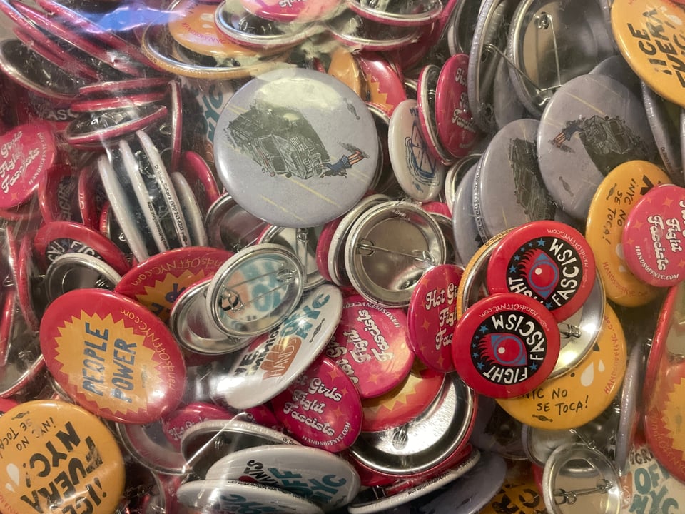 cool pile of buttons from Hands Off NYC that say things like "PEOPLE POWER" "FIGHT FASCISM" "ICE FUERA NYC!" and "Hot Girls Fight Fascists"