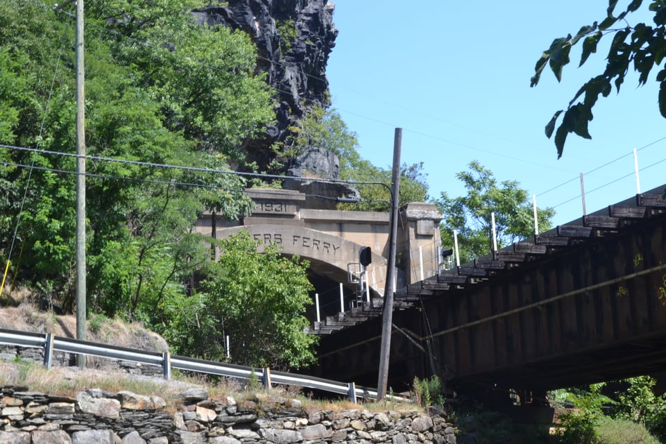 A railroad bridge that ends at a tunnel portal marked with the words "Harpers Ferry"