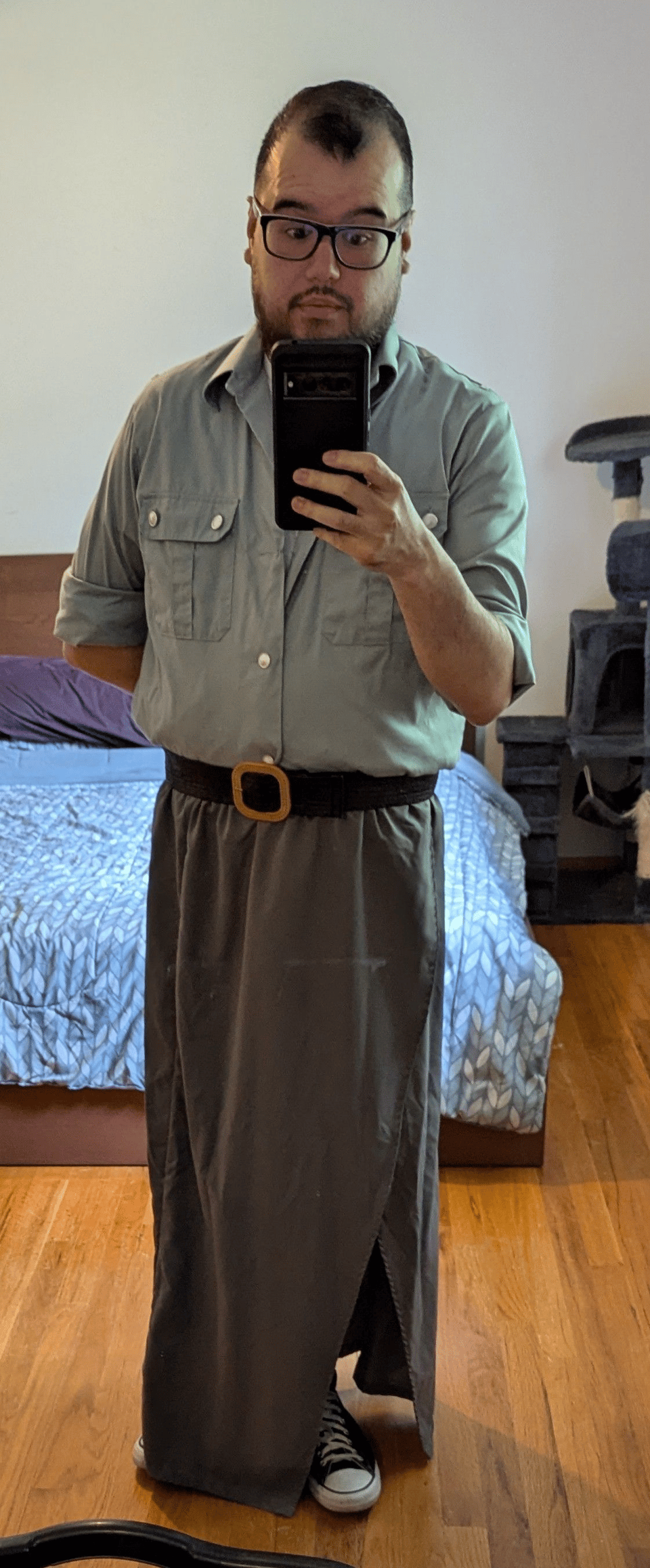 A selfie of Mikkel wearing a pale green button up and grey skirt.