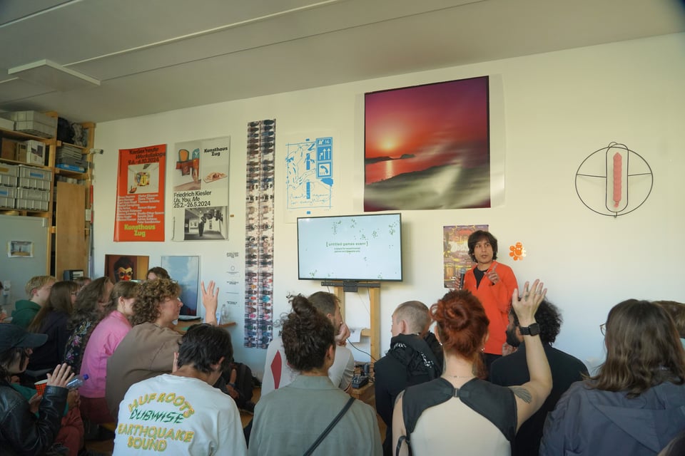 a man in an orange shirt points to an audience member with their hands raised