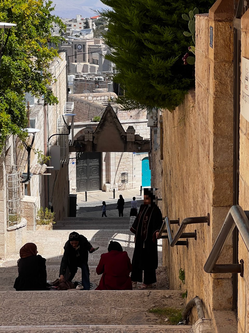 A stone stairway between buildings with four people, one in a graduation cap and gown